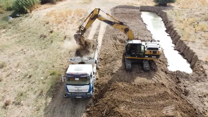 Pelle mécanique chargeant un camion près d’une zone contenant de l’eau